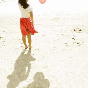 手中的气球：海滩上，女孩手中的三色气球